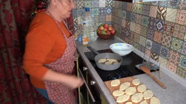 Büyükannem tavada kızgın yağda turta pişiriyor. Kızarmış turta, ev yapımı hamur yemeği. Kadın mutfakta yemek pişiriyor..