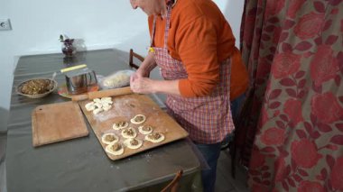 Yaşlı bir kadın etli börek yapar. Ev yapımı hamur. Büyükannem evde yemek pişiriyor.