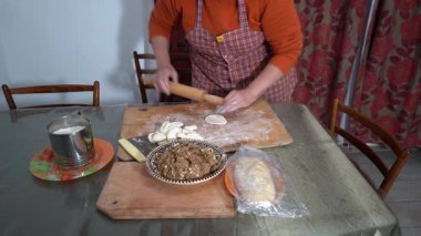 Kadınların elleri hamuru tahta bir oklavayla çevirir. Etli turta yapıyorum. Büyükannem yemek pişiriyor. Masada un var.