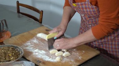 Kadınların elleri hamuru porsiyonlu pastalara kesiyor. Büyükannem evde undan yemek pişirir. Yemek masası