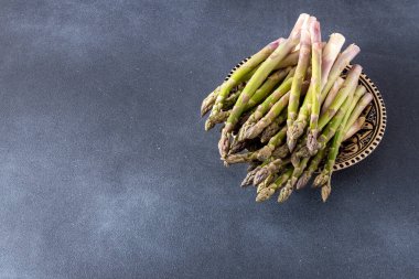 Koyu arkaplanda yeşil kuşkonmaz. Sebze filizleri. Taze yemek kasesi manzarası. Boşluğu kopyala.