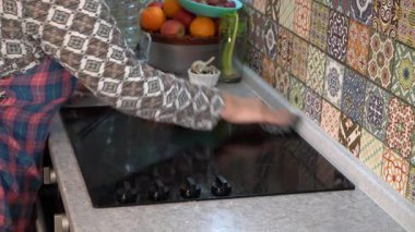 Yaşlı kadın musluğu yıkıyor ve mutfakta lavabo açıyor. Evde önlüklü bir büyükanne. Ev işi.