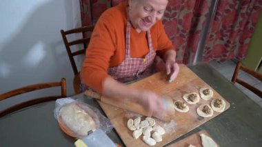 Kadınların elleri hamuru tahta bir oklavayla çevirir. Etli turta yapıyorum. Büyükannem gülümsüyor ve yemek pişiriyor. Tahta.