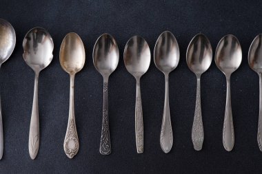 Farklı kaşıklar. Siyah arka planda gümüş çatal bıçak seti. Masadaki kaşık.