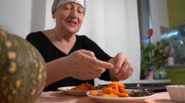 Yaşlı bir kadın tohumları taze bir balkabağından ayırıyor. Bir büyükanne mutfaktaki masada yemek hazırlar. Ev yemeği. Büyükanne konuşuyor.