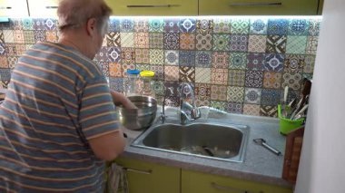 Yaşlı bir kadın yemek hazırlıyor. Mutfak yüzeyinde patates doğrama. Büyükannem evde yemek yapıyor.