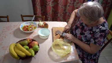 Yaşlı bir kadın mutfakta balık yemeği hazırlıyor. Tahtayı kesiyor. Ringa balığı