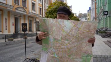 Yaşlı bir kadın sokakta dururken bir şehir haritasına bakıyor. Gezgin büyükanne. Büyükanne yürüyor.