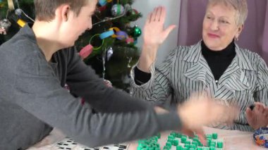 Yaşlı kadın emekli bingo oynuyor. Torunuyla evde masa oyunu oynayan bir büyükanne. Piyango. Birlikte zaman geçirmek. Onlar sevinçle ellerini çırpar ve gülerler. Selamlıyorlar ve tebrik ediyorlar..