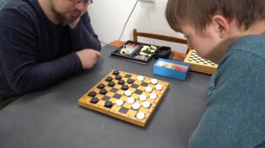 Dama oynayın. Ergen çocuk babasıyla masa oyunu oynuyor. Ailecek vakit geçirmek..