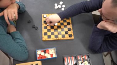 Dama oynayın. Ergen çocuk babasıyla masa oyunu oynuyor. Ailecek vakit geçireceğiz. El sıkışın..
