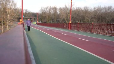 Yaşlı bir kadın köprüde yürüyor. Bir büyükanne soğuk rüzgarlı havada yürür. Sokak dışı.