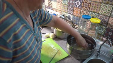 Yaşlı bir kadın yemek pişiriyor. Bıçaklı eller. Mutfak yüzeyinde patates doğrama. Büyükanne yemek pişirir Sebze keser.