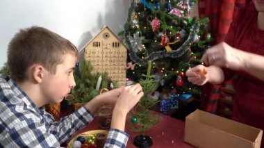 Büyükanne ve torun küçük bir Noel ağacını eski Noel ağacı oyuncaklarıyla süsler. Birlikte vakit geçirmek. El sanatları. Noel tatili için ev dekorasyonu. Aile zamanı.