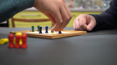 Zarı at ve taşları oynat. Tahta Oyun kuralları. Oyuncuların elleri oynuyor