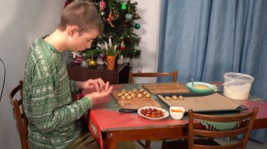 Bir çocuk kurabiye yapar. Bir genç hamurun içine badem koyar. Yemek pişirmek. Mutfak masası.