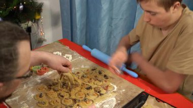 Baba oğul kurabiye yapıyor. Erkek ve genç çocuk evde yemek pişiriyor. Hamur masada. Pasta hamur işleri