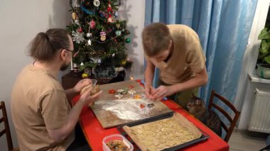 Bir adam ve bir genç çocuk hamurdan kurabiye kesiyorlar. Baba ve oğul birlikte yemek pişiriyorlar. Baba aşçı. Evde kedi var. Noel yemeği