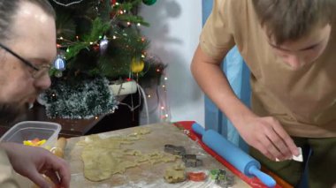 Bir adam ve bir genç çocuk hamurdan kurabiye kesiyorlar. Baba ve oğul birlikte yemek pişiriyorlar. Babam evde yemek yapıyor. Noel pastası.
