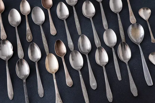 Farklı kaşıklar. Siyah arka planda gümüş çatal bıçak seti. Kaşığı masaya koy. Sofra takımı yemek servisi.
