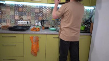 Baba ve oğul yemek pişirdikten sonra mutfağı temizler. Adam bulaşıkları yıkar. Ev ödevi