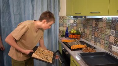 Ergen fırına kurabiye tepsisi koyar. Bir çocuk evde yemek pişirir. Mutfakta pişmiş kurabiye. Pişirme