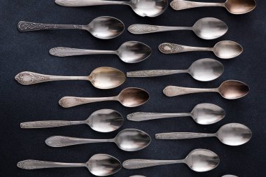 Farklı kaşıklar. Siyah arka planda gümüş çatal bıçak seti. Yemek servisinde kaşık var.