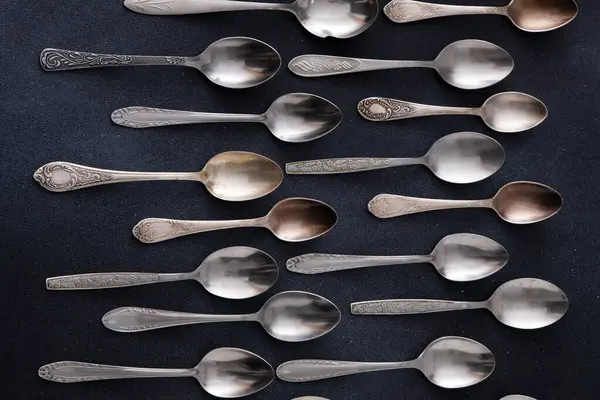 Farklı kaşıklar. Siyah arka planda gümüş çatal bıçak seti. Yemek servisinde kaşık var.