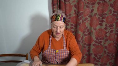 Yaşlı bir kadın etli börek yapar. Tahta merdane. Ev yapımı hamur. Büyükannem evde yemek pişiriyor. Büyükannem mutfakta.