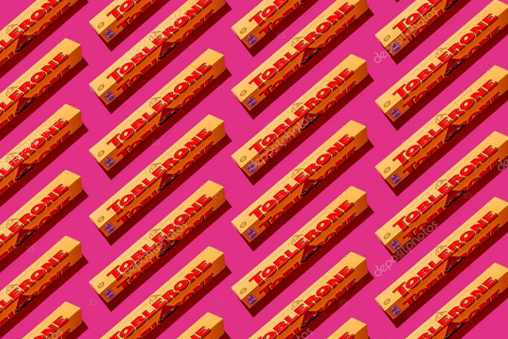 Toblerone brand chocolate packaging. Swiss Mondelez candy. Yellow pack on pink background top view pattern. Ukraine, Kyiv - November 4, 2024.