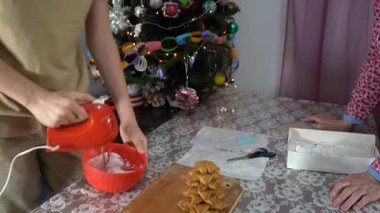 Karıştırıcıyla karıştır. Kırmızı Noel Baba şapkalı genç aşçı. Bir çocuk Noel yemeği için evde kurabiye pişirir. Pudra şekeri ve beyaz krema..