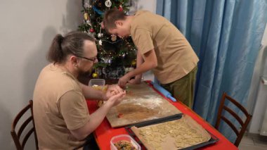 Bir adam ve bir genç çocuk hamurdan kurabiye kesiyorlar. Baba ve oğul birlikte yemek pişiriyorlar. Babam yemek yapıyor..