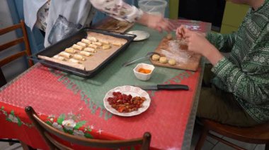 Hamurdan kurabiye yap ve bir yemek tepsisine koy. Evde yemek pişir. Doldurulmuş pişmiş yiyecekler. Ellerini masaya koy. Noel yemeği