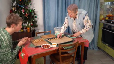 Çocuk kurabiye ve turta yapıyor. Mangır çıkarıyorum. Ergen, büyükannenin Noel için yemek yapmasına yardım ediyor. Ev mutfağında pişirme..