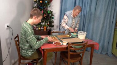 Çocuk kurabiye ve turta yapıyor. Mangır çıkarıyorum. Ergen, büyükannenin Noel için yemek yapmasına yardım ediyor. Ev mutfağında yemek pişirmek