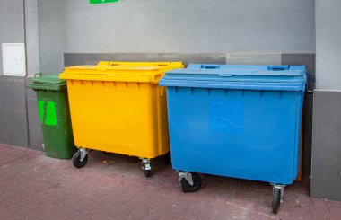 Çöp ayıklama. Plastik çöp kapları mavi, sarı, yeşil renklerde. Atıkları geri dönüştür. Sokaktaki Çöp Kutuları