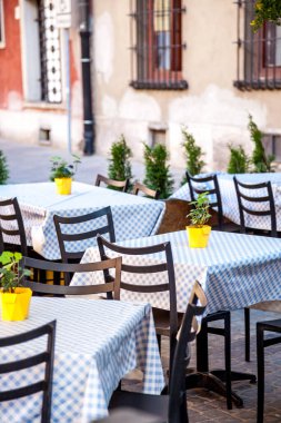 Açık havada boş kafe koltukları. Sandalyeler ve masalar. Summer Street Bar verandasındaki eski bir turist kasabası. Masa örtüsü