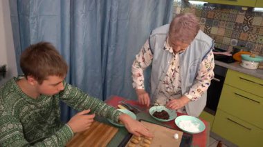 Çatlaklı çikolatalı mermer kurabiyeler yap. Oğlan ve büyükanne hamur işi pişiriyor. Ergen ve yaşlı kadın yemek pişirir. Hamuru pudra şekerinde yuvarla..