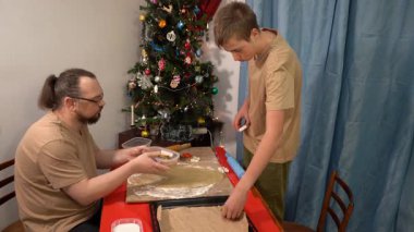 Turtayı hamurun üzerine koy. Baba oğul kurabiye yapıyor. Adam ve çocuk masada oturuyor. Noel yemeği hazırlıyorum. Aile bir arada. Pasta..
