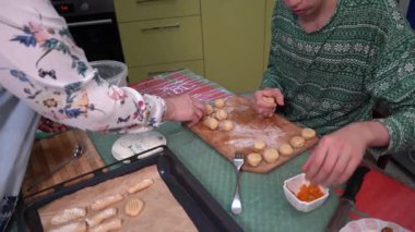 Gençler kurabiye pişiriyor. Mangırı büyükannem yapıyor. Noel kurabiyesi pişir. Bir çocuk mutfakta yemek hazırlıyor. Yemek tepsisi masada.