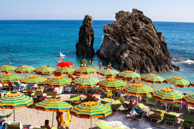 Yazın sahilde şemsiyeler. İtalyan bayramı. Ligurian Denizi kıyısında tatiller. Liguria Cinque Terre kayalığı. İtalya, Monterosso - 15 Temmuz 2025.