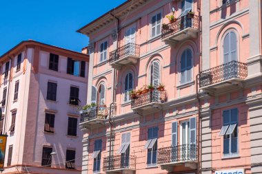 Pembe renkli evin balkonundaki İtalyan panjurları. Yazın ahşap kepenkleri açın. Mimari La Spezia şehir binası.