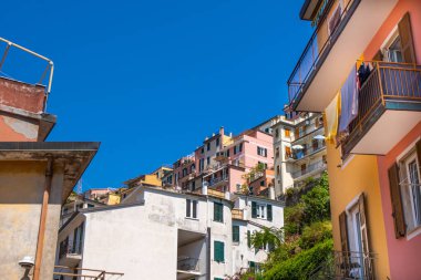 Pembe turuncu renkli evin balkonundaki İtalyan panjurları. Yazın ahşap kepenkleri açın. Mimarlık binası. Cinque Terre mavisi.
