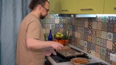 Adam bir spatulayla birlikte bir tepsiye kurabiye koyar. Ev yapımı kek. Yemek pişir.