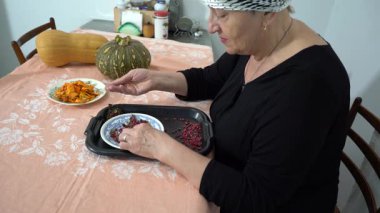 Kuru çilek. Yaşlı bir kadın kurutulmuş böğürtlen hasadını sınıflandırıyor. Bir büyükanne mutfaktaki masada yemek hazırlar. Ev yemeği..