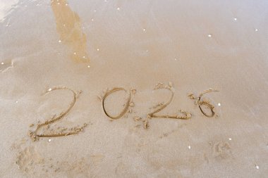 Kuma yazılmış 2026 numara. Plajda yeni yıl golü. Deniz arka planı. Boşluğu kopyala