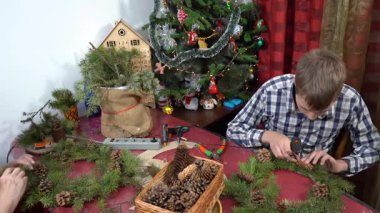 Büyükannem ve torunum birlikte Noel çelengi yapıyorlar. Yapıştırıcı kozalakları. Yaşlı kadın ve genç çocuk dekore ediyor. Aile Zirvesi