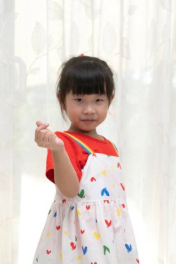Young cute Asian girl making heart symbol by hand.