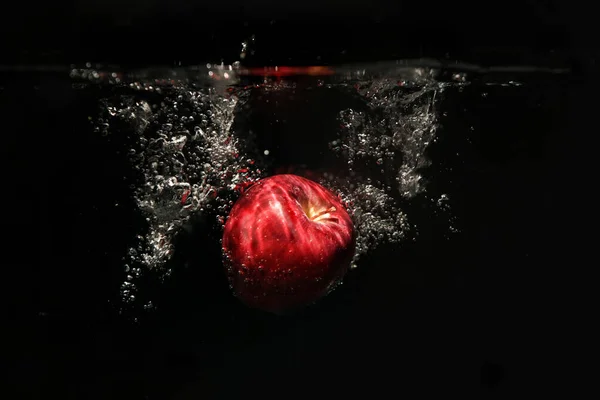 사과가 물거품 속으로 떨어지고 배경에 — 스톡 사진