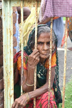 RAJGIR, BIHAR, INDIA - 02 Ağustos 2023: Tanımlanamayan yaşlı bir kadın kapıdan dışarı bakıyor